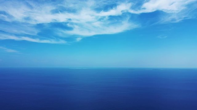 horizon shot of open blue turquoise tropical ocean under a bright blue sky with white clouds, Aerial drone