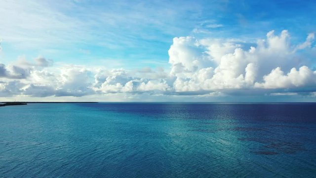 horizon shot of open blue turquoise tropical ocean under a bright blue sky with white clouds, Aerial drone chot