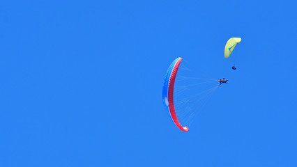 Paragliding. Two paragliders on a blue sky background. Copy space.