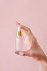Beautiful groomed woman's hands with serum bottle mock up on a light background.
