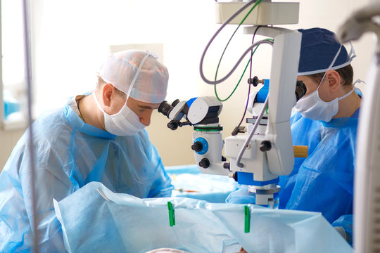 Two ophthalmologist perform an operation in the operating room, delicate work with the eyes, eye surgery, two scientists look through microscopes