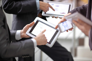 Businessmen at meeting presenting charts on smartphone, tablet