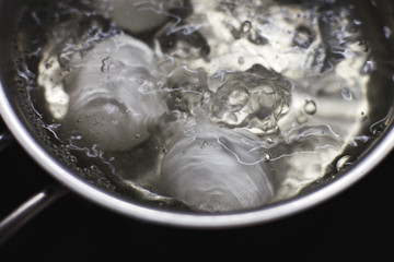 chicken eggs boil in water.  eggs are cooked in a saucepan on the stove.