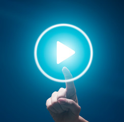Female finger pushing transparent play button on blue