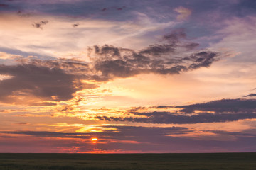 A colorful, picturesque sky above the field during the sunset_