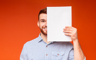 Young smiling man covering half of his face beside white sheet