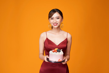 Vertical shot of an elegant woman in a red dress carrying a birthday cake