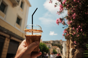 hand of man holding a typical coffee cup area in a sunny day in the capital of Greece - Athens.
