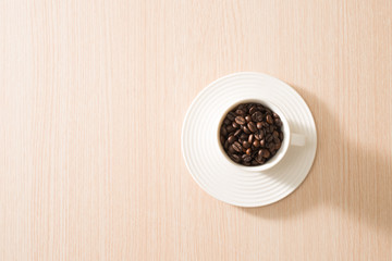 Cup of full coffee beans on the wood background