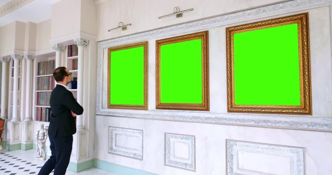 Man in gallery room looking at empty picture frames