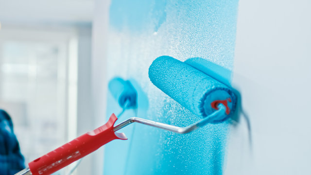 Close-Up Shot of a Wall Being Painted with a Roller. Color of the Paint is Light Blue. Flat Renovations at Home.