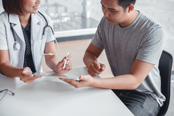Professional doctor consulting young male patient. Doctor using tablet to diagnostic examination on men's health disease in clinic or hospital office. Medical technology concept.