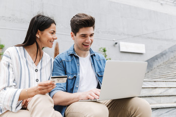 Happy young amazing loving couple business people colleagues outdoors outside using laptop computer...