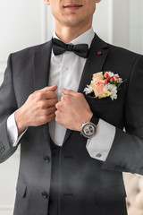The groom in a white shirt, tie, black or dark gray and costume. Young man with a beautiful boutonniere of pink roses or chrysanthemums and green leaves, on the lapel of his jacket. Wedding theme