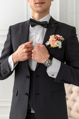 The groom in a white shirt, tie, black or dark gray and costume. Young man with a beautiful boutonniere of pink roses or chrysanthemums and green leaves, on the lapel of his jacket. Wedding theme