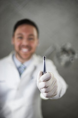 Male smiling dentist holding a drill POV