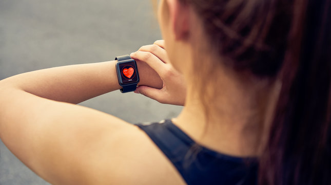 Young woman checking the sports watch measuring heart rate and performance after running.