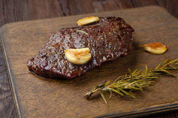 Beef steak with twig rosemary on a wooden table.