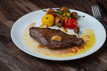 Rib-eye steak with baked vegetables resting on a white plate