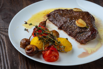 Rib-eye steak with baked vegetables resting on a white plate
