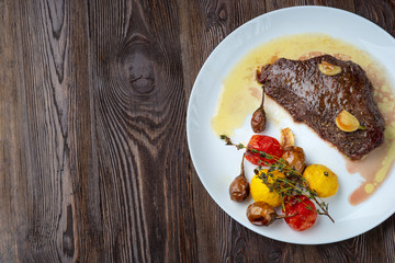 Rib-eye steak with baked vegetables resting on a white plate