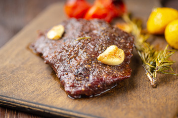 Grilled rib eye  steak with spices  served on a wooden board with baked vegetables