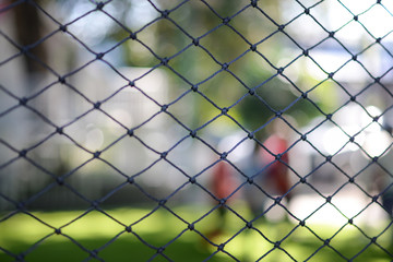 Looking through a net.Selective focus on a football net with blur background.A stretched net with people in the background.