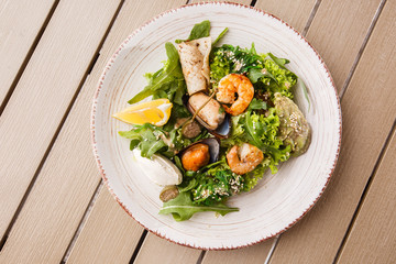 Healthy Salad. Recipe for fresh seafood. Grilled shrimps, mussels and squid, fresh salad lettuce and avocado puree. Healthy Eating. Wooden background