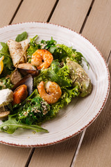 Healthy Salad. Recipe for fresh seafood. Grilled shrimps, mussels and squid, fresh salad lettuce and avocado puree. Healthy Eating. Wooden background