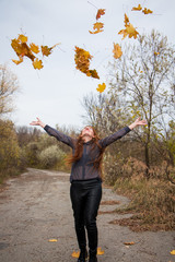 Fototapeta na wymiar young redhead woman in autumn park. autumn yellow leaves