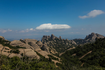 Fototapeta na wymiar Mountains of Montserrat in Catalonia, Spain. Beautiful top vie on the green hills and stones. Sky and rocks. Panoramic view on the hills and nature in Montserrat 