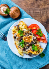 omelette with mushrooms in white plate on wooden table background