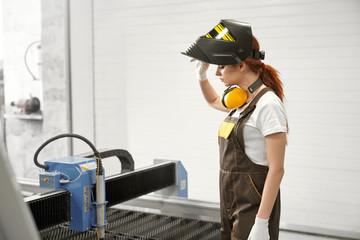 Female mechanic in protective mask standing near cnc