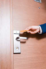 Naklejka premium cropped view of businessman holding hotel card near door