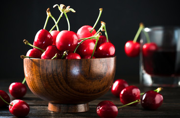 Red sweet cherries in a bowl on a wooden background