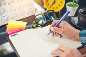 On Calendar page,Female hand planner or organizer writing daily appointment.Woman mark and noted...