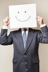 Businessman with a smile on a paper covering his face