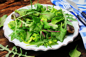 Mix fresh leaves of New Zealand spinach, arugula, lettuce, , beets for salad on a dark wooden background. Top view