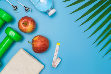 Top view healthy object on blue background with dumbbells, water and earphones for sport or exercise concept.