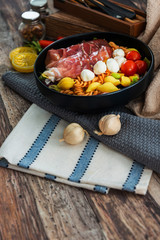 Salad made with cooked pasta, mixed green salads, cherry tomatoes, Mozzarella cheese and smoked ham served with accompaniment