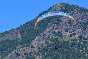 Paragliding. Paragliders on a blue sky and mountains background.