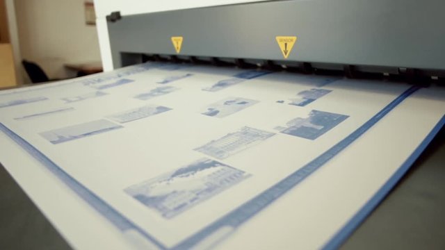 Printed sheet of paper coming out from printing machine. Offset printing, CMYK, close up