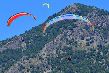 Paragliding. Paragliders on a blue sky and mountains background.