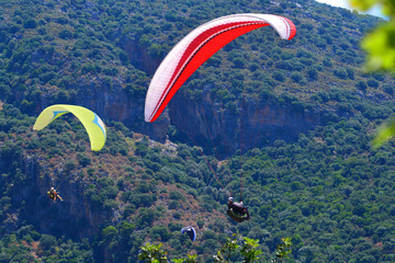 Paragliding. Paragliders on a blue sky and mountains background.