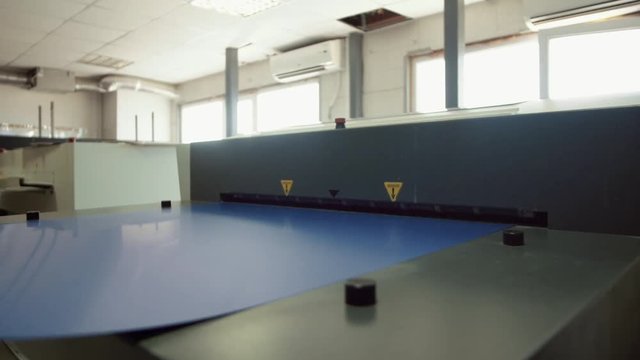 Printed sheet of paper coming out from printing machine. Offset printing, CMYK, close up