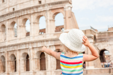 little girl points the finger at the coliseum  in rome, italy. Back view