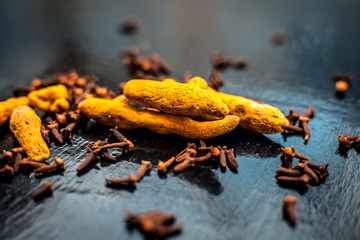 Face mask or pack’s ingredients on wooden surface for acne which are turmeric or haldi and cloves. Ingredients spread on the surface. Horizontal shot.