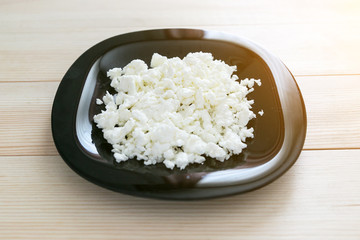 Delicious and healthy breakfast - milk cottage cheese. Cottage cheese on a black glass plate.