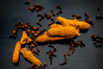 Face mask or pack’s ingredients on wooden surface for acne which are turmeric or haldi and cloves. Ingredients spread on the surface. Horizontal shot.