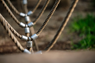 Abstract picture shot on a playground at a climbing fram with a detail with bright beige ropes connected via metal. Seen in Nuremberg, Germany, June 2019
